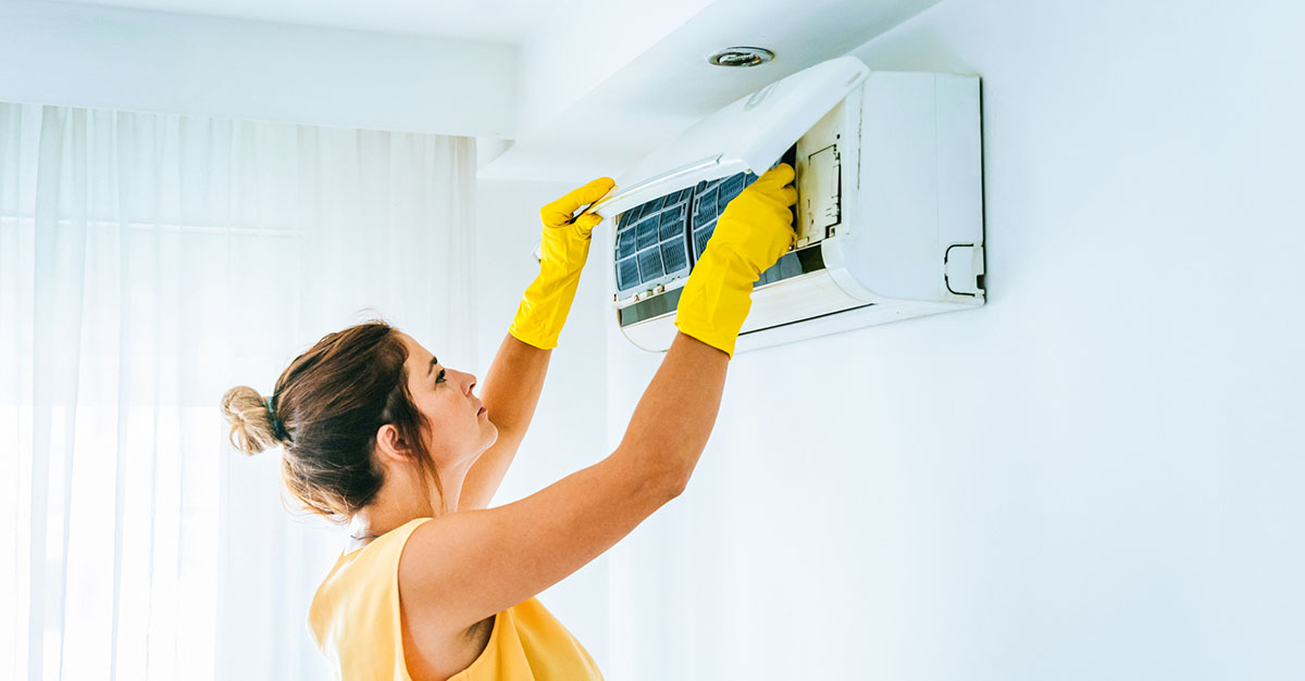 A woman changing the filter on her air conditioner