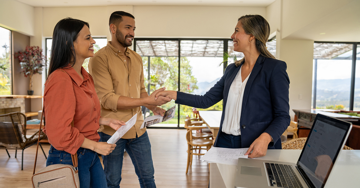 An agent shakes hands with her clients in a new home